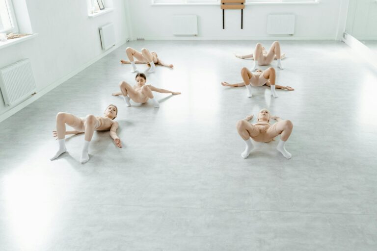 Children performing a dance routine in a ballet studio, focusing on flexibility and form.